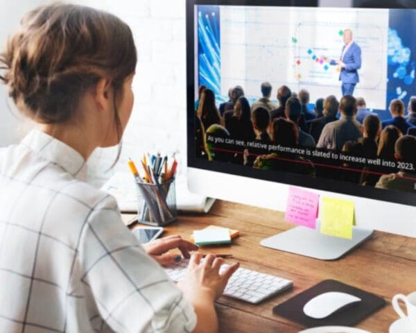 Person watching a live event on a computer with captions displayed on the screen.
