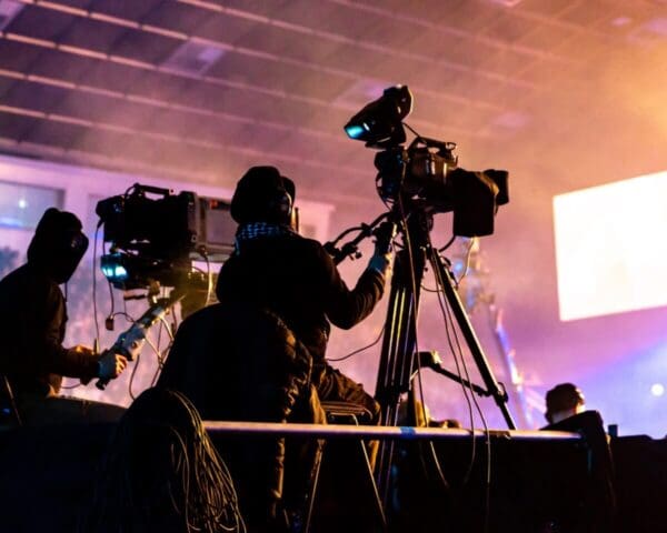 Two people using broadcast cameras to film a live event.